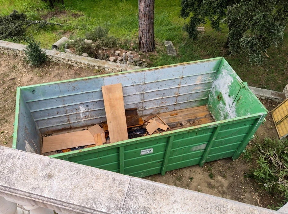 Benne de chantier verte vue en plongée, placée en extérieur sur terrain naturel