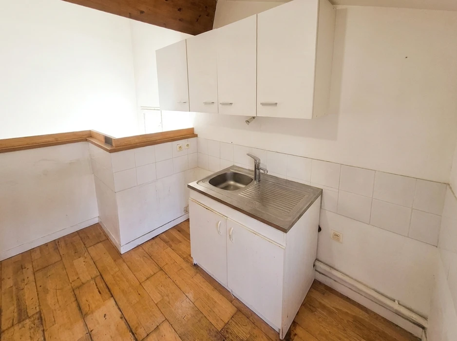Extérieur d'une maison en rénovation avec un benne à déchets métallique verte de type skip container posée sur le sol