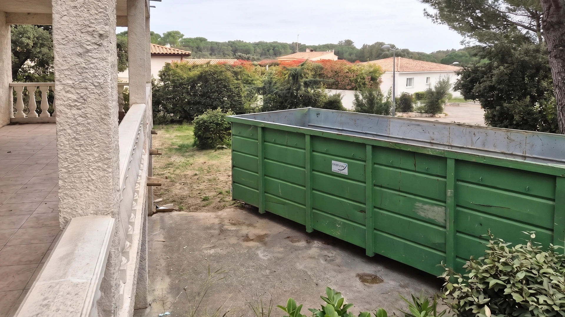 Scène extérieure de chantier avec benne verte contenant gravats de démolition : briques rouges perforées, débris de maçonnerie